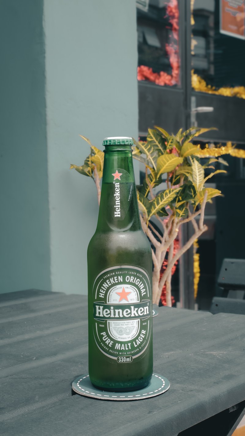 Uma garrafa de cerveja gelada sobre a mesa da sala de espera, ao lado de uma planta.